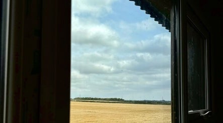 View from Calmia Treatments window showing fields in Stamford, England, GB under a cloudy sky.
