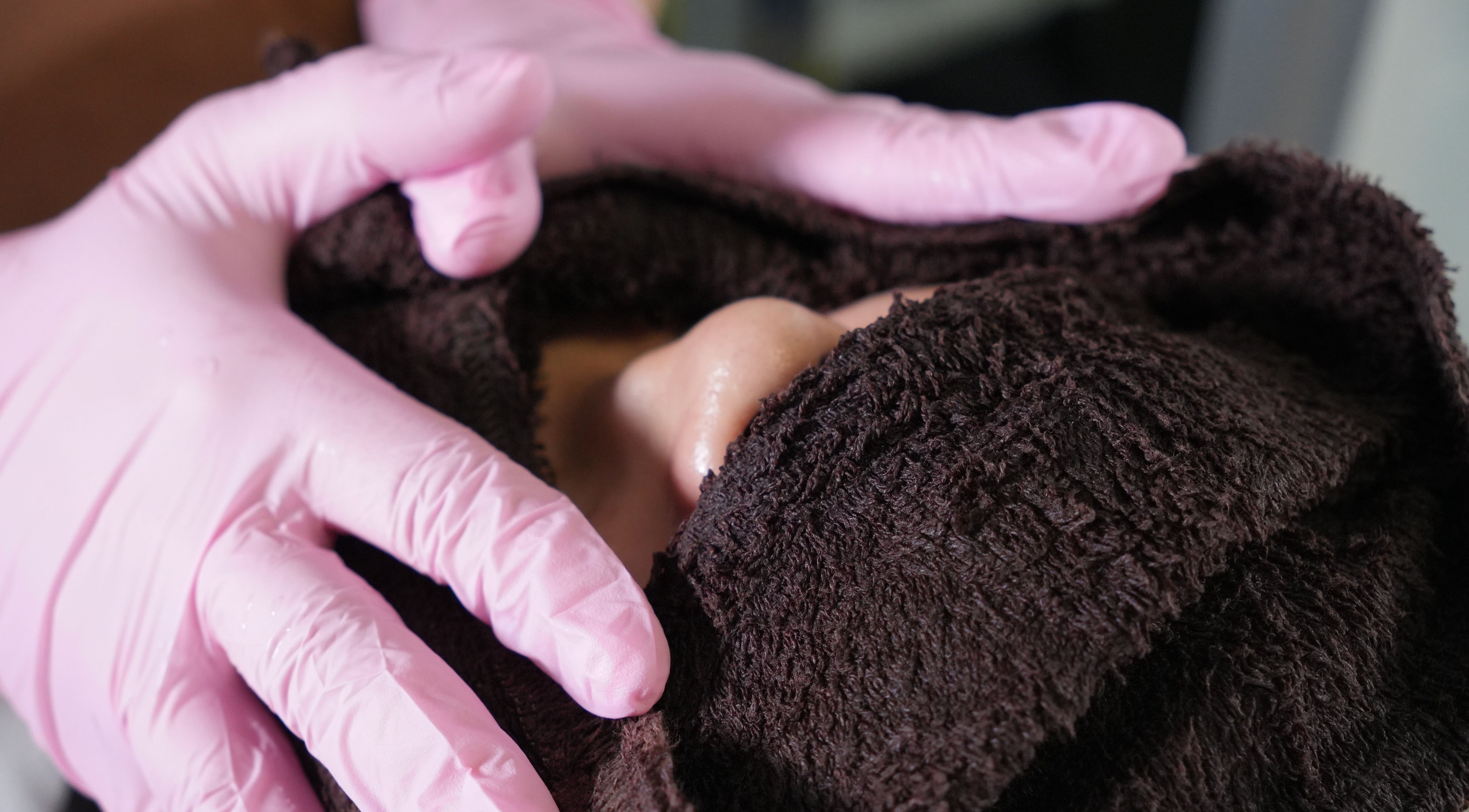 Soins du visage chez CK Glow à Laval, Québec, CA avec serviette chaude et gants roses.