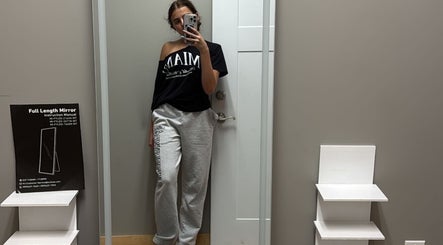 Person posing by mirror at TEKH HAIR STUDIO LLC, Hilton, New York, US, showcasing modern studio interior.