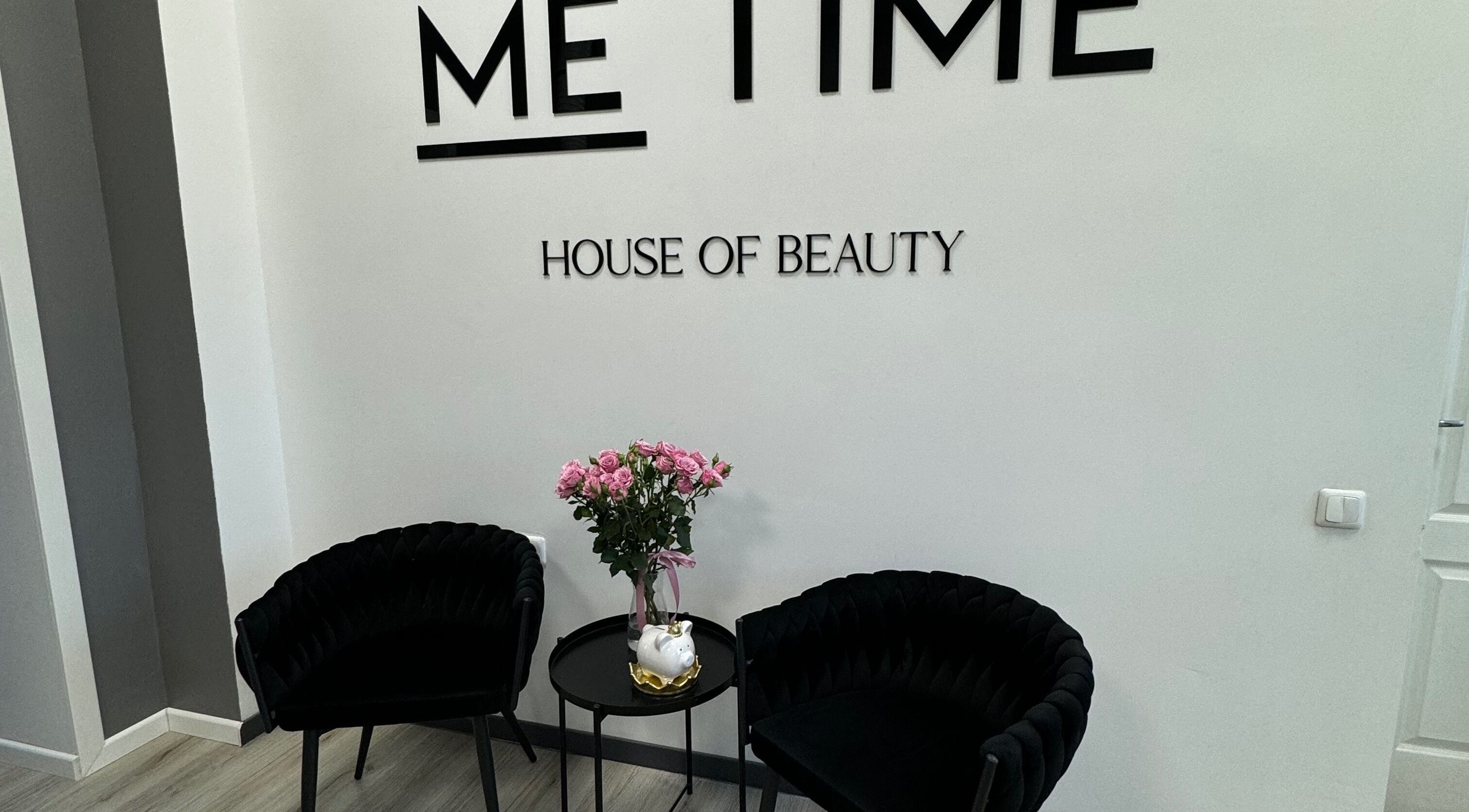 Elegant lounge area at ME TIME STUDIO in Jelgava, LV featuring black chairs and a floral arrangement.