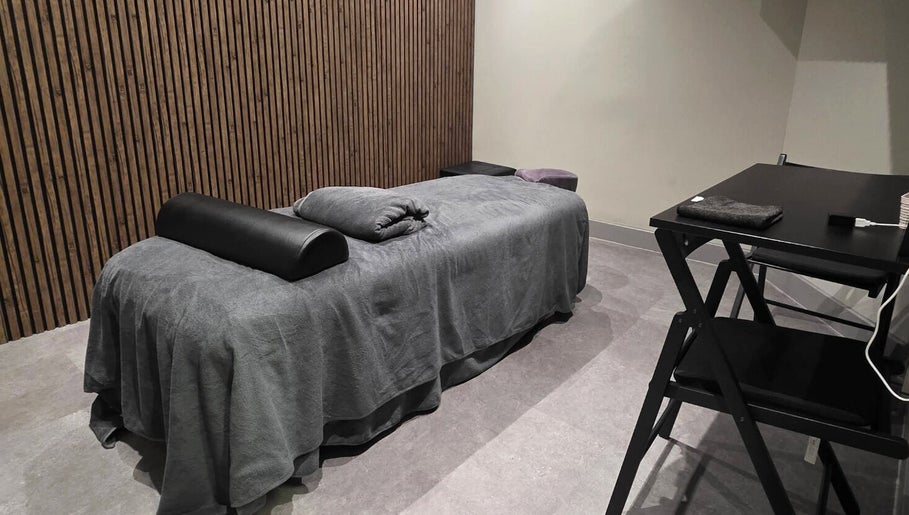 Rustige massageruimte in Tension Treat, Amsterdam, Noord-Holland, NL met comfortabele tafel en houten wand.