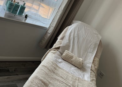 Relaxation room at Tame, Motherwell, Scotland, GB with a comfy massage table and skincare products.