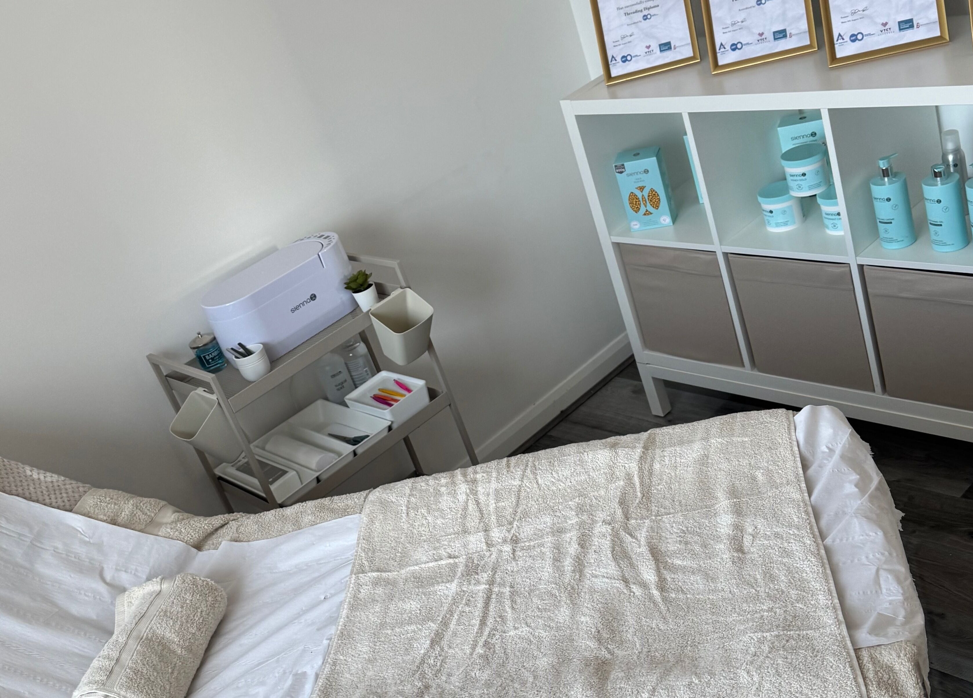 Relaxing treatment room at Tame in Motherwell, Scotland, GB, showcasing cozy linens and premium skincare products.