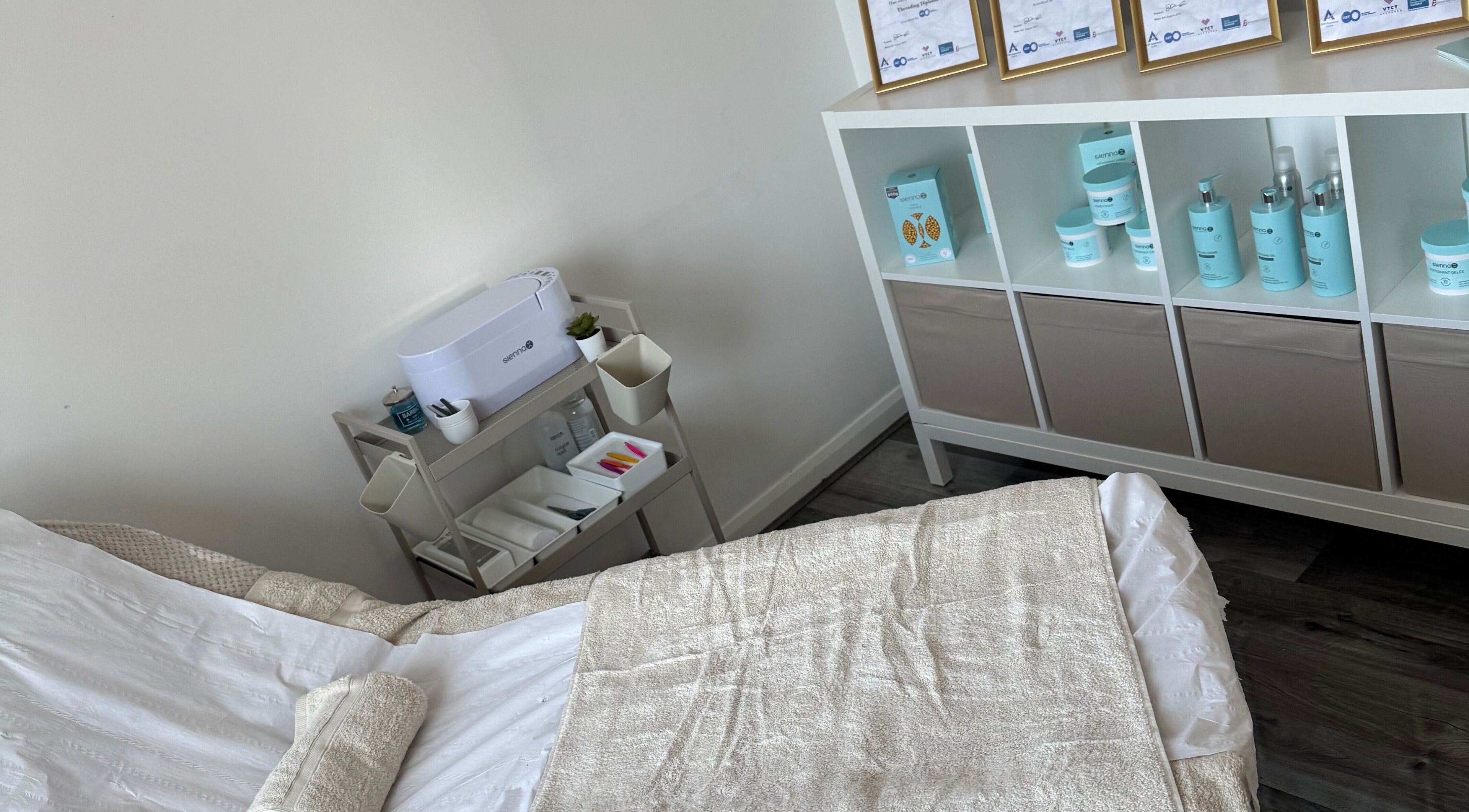 Relaxing treatment room at Tame in Motherwell, Scotland, GB, showcasing cozy linens and premium skincare products.