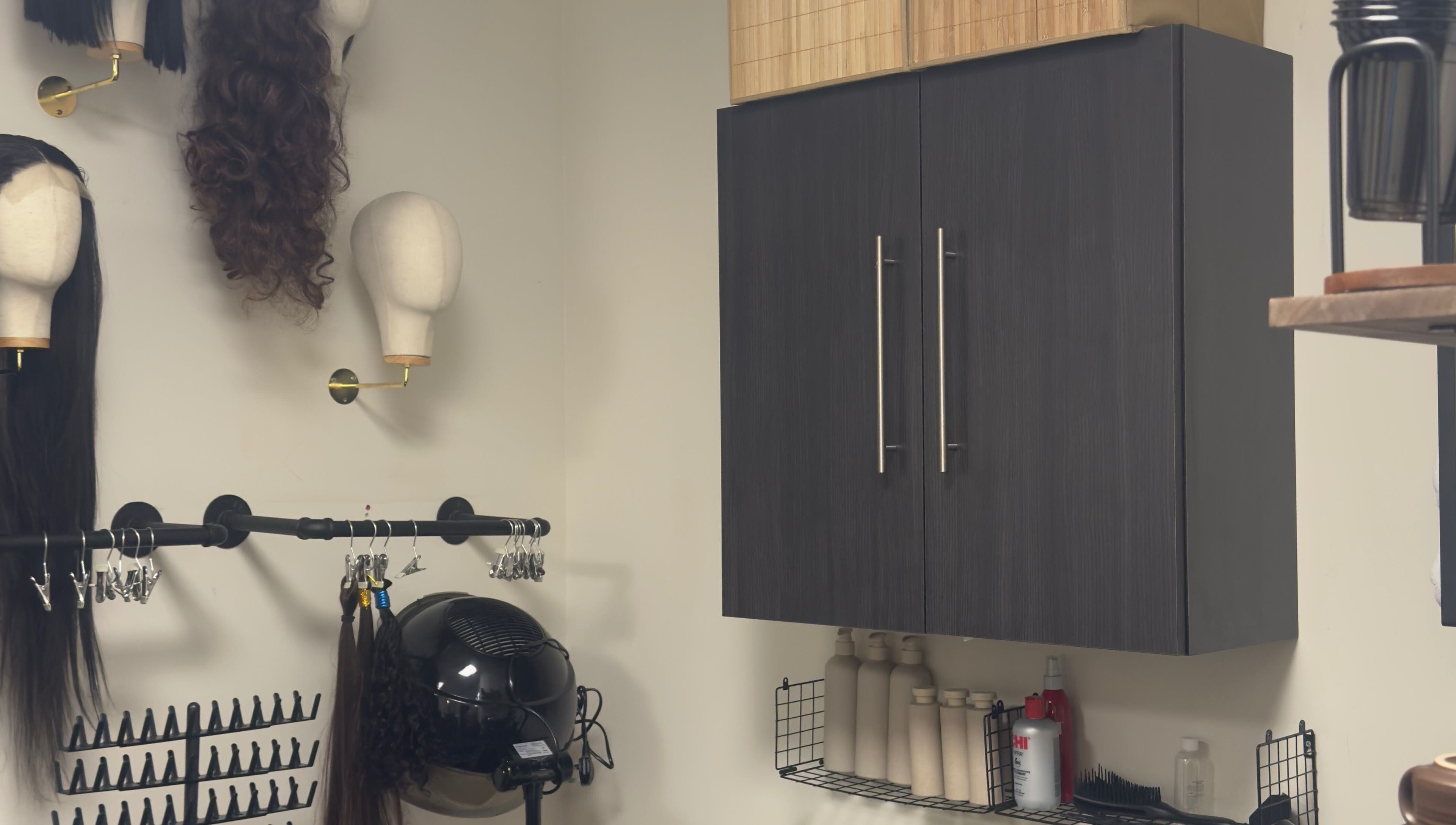 Wig display and styling tools at TheBeautyVine, Birmingham, England, GB. Modern salon decor and storage cabinets.