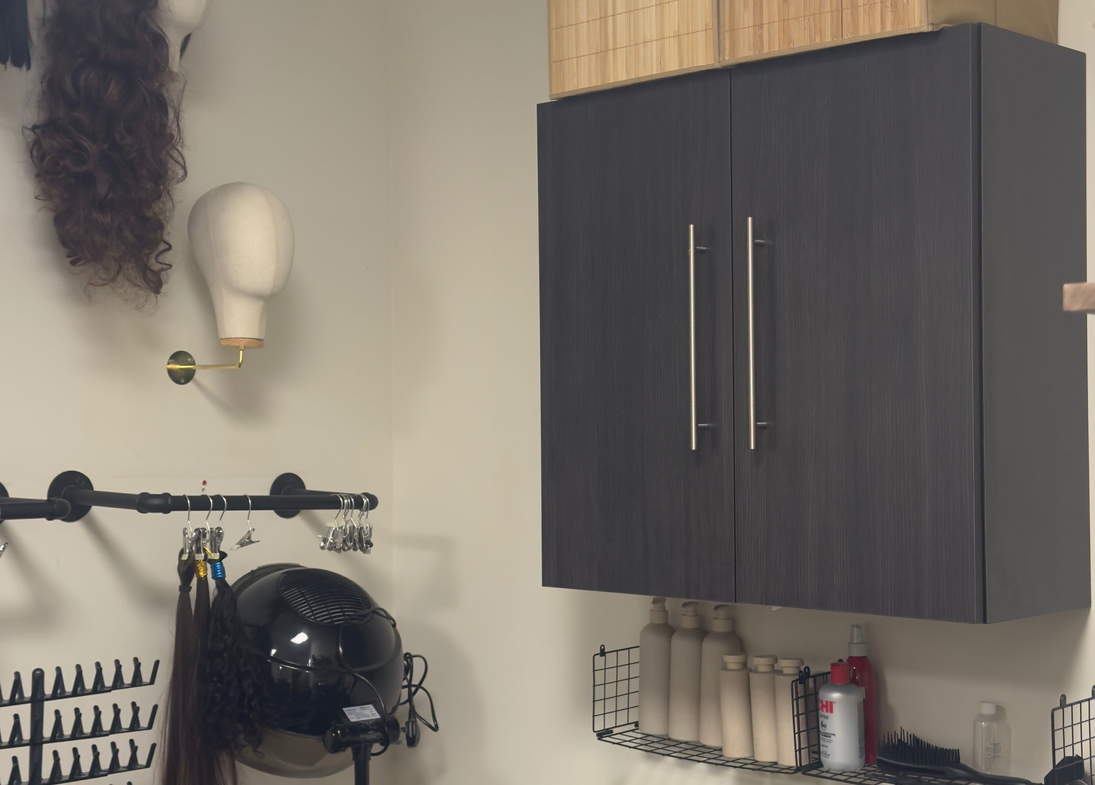 Wig display and styling tools at TheBeautyVine, Birmingham, England, GB. Modern salon decor and storage cabinets.