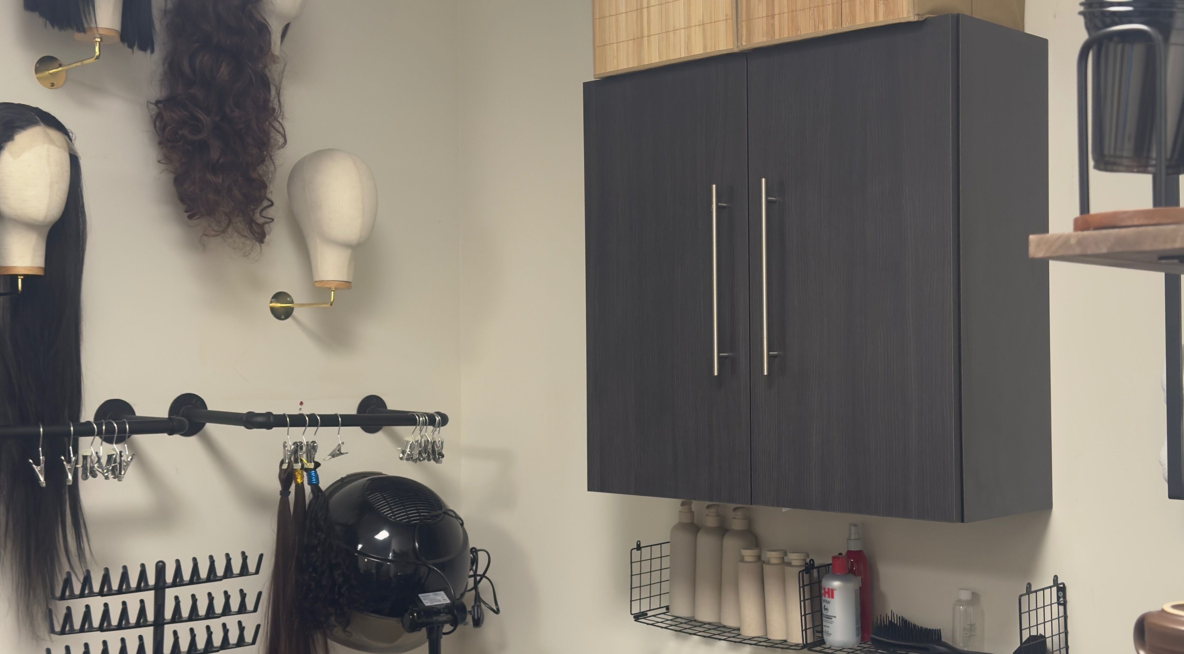 Wig display and styling tools at TheBeautyVine, Birmingham, England, GB. Modern salon decor and storage cabinets.