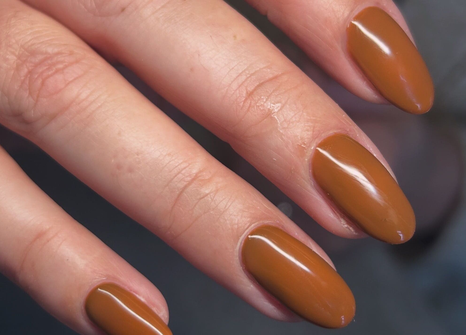 Elegant bronze manicure at Femme Lounge, South Lanarkshire, Scotland, GB, showcasing glossy nail art.