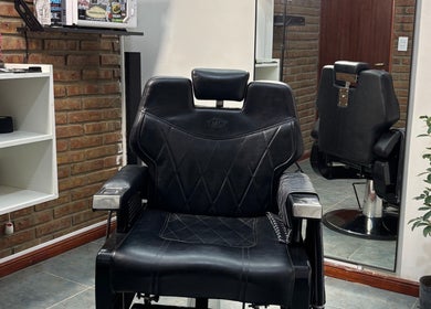 Silla de barbero en Encon Estudio, Neuquén, Neuquén, AR, con fondo de ladrillos y espejo.