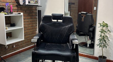 Silla de barbero en Encon Estudio, Neuquén, Neuquén, AR, con fondo de ladrillos y espejo.
