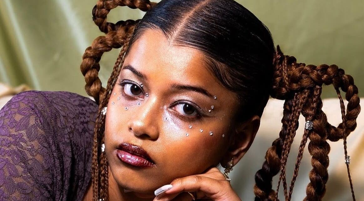 Intricate braided hairstyle at Tinyscosmetics, Enfield, England, GB featuring bold makeup and rhinestones.