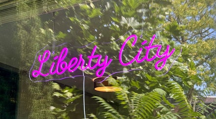 Neonbord van Liberty City Nail Studio weerspiegeld op een raam, Amersfoort, Utrecht, NL.