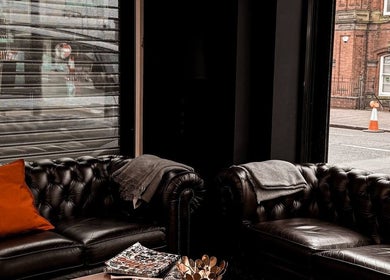 Elegant black leather sofas in VEAN Tattoo lounge, Wolverhampton, England, GB, perfect for relaxation.