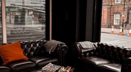 Elegant black leather sofas in VEAN Tattoo lounge, Wolverhampton, England, GB, perfect for relaxation.
