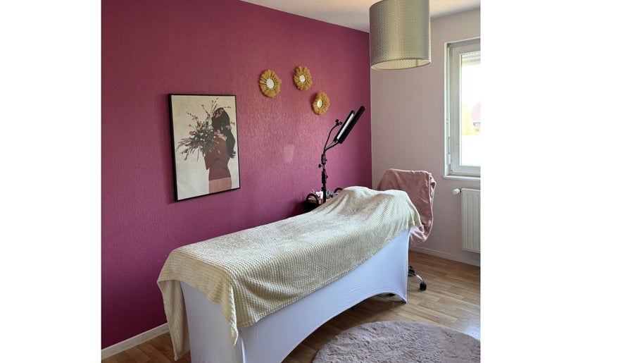 Salle de soin chez Amondomicils à Florange, Grand Est, FR avec mur rose et lit de massage.