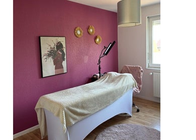 Salle de soin chez Amondomicils à Florange, Grand Est, FR avec mur rose et lit de massage.
