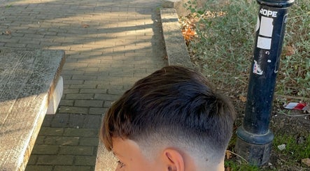 Corte moderno de cabelo curto em jovem na G Barbershop, Alcabideche, Lisboa, PT, com fundo de rua arborizada.
