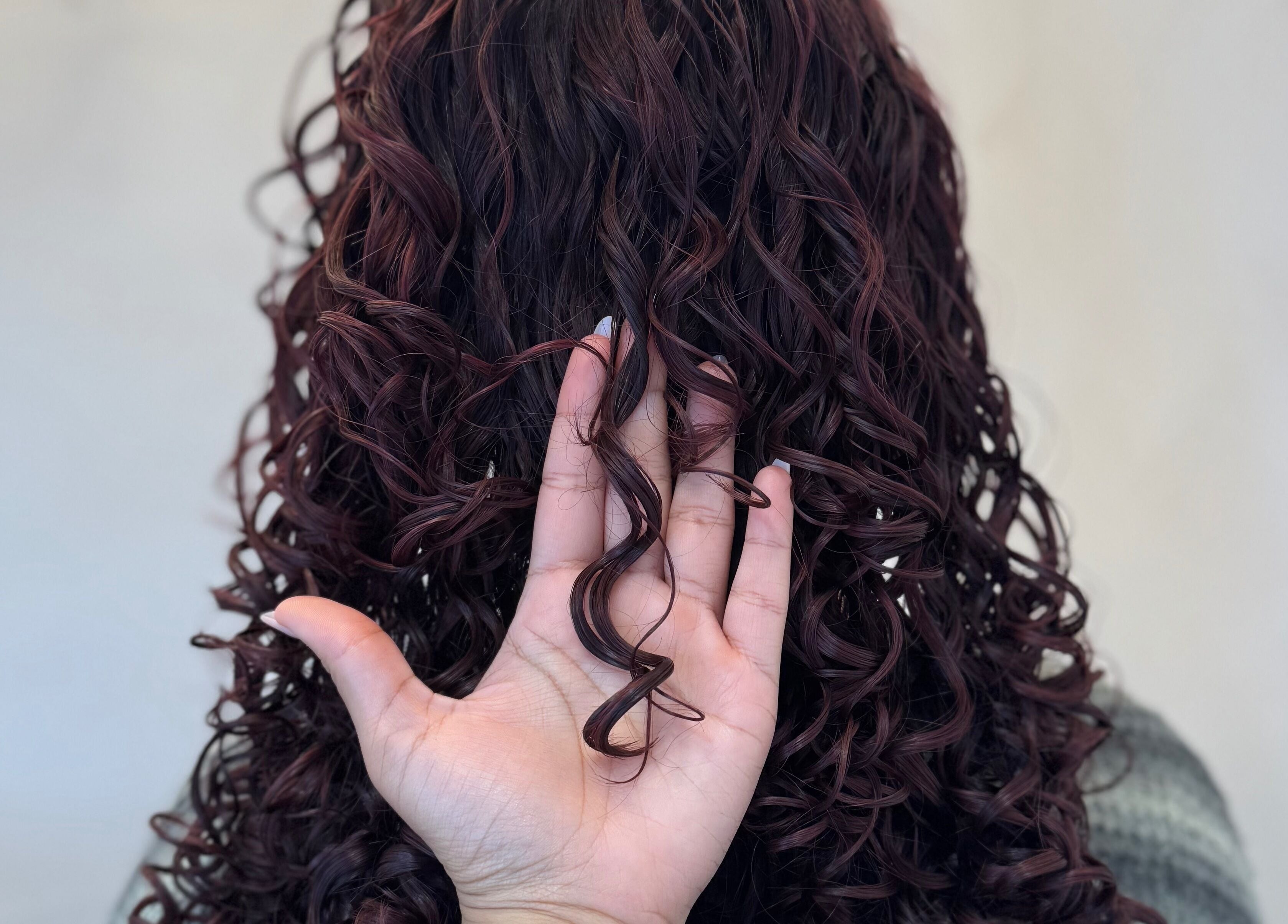 Close-up of hand holding a curl at Monetlillyhair in Clifton, England, GB, showcasing lush, defined curls.