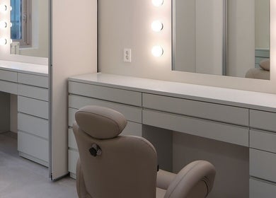 Elegant beauty station at HE:ARTS Dosan, Seoul, 서울특별시, KR with luxurious seating and illuminated mirrors.