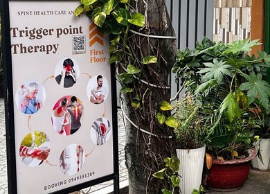 Bảng quảng cáo trị liệu đau điểm tại YEN THERAPY, Hồ Chí Minh, VN với cây cối xanh tươi xung quanh.