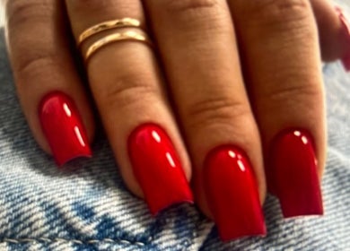 Red manicured nails on denim at Noran Beauty Academy, נוף הגליל, מחוז הצפון, IL.