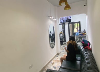 Sala de espera moderna en Europa Barber Shop, Neiva, Huila, CO, con sofá negro y espejo ovalado.