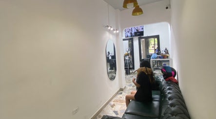 Sala de espera moderna en Europa Barber Shop, Neiva, Huila, CO, con sofá negro y espejo ovalado.