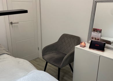 Inviting treatment room at Lashed By Lilya, Southend-on-sea, England, GB with a grey chair and a lit candle.