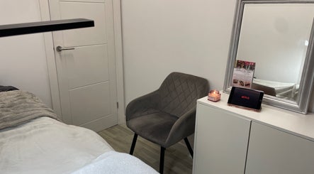 Inviting treatment room at Lashed By Lilya, Southend-on-sea, England, GB with a grey chair and a lit candle.