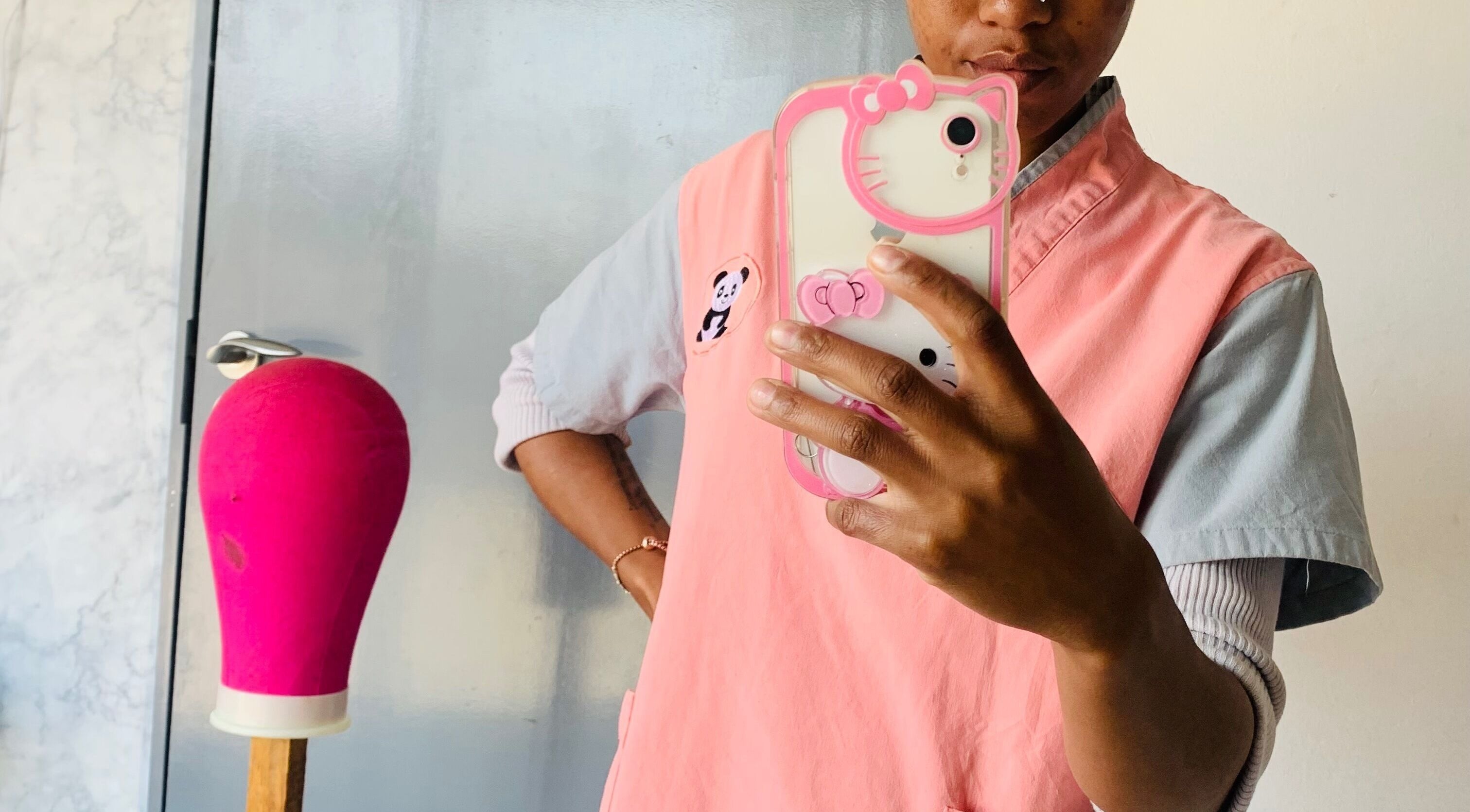 Nailed.By.Manana staff in pink apron, Alexandra, Gauteng, ZA, taking a selfie beside a pink mannequin head.