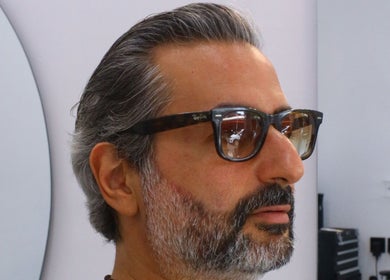Man with styled beard at Umatura Barber Canggu in Bali, Bali, ID, looking into a mirror.