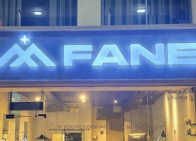 Illuminated sign of Fane Barbershop at night in Jeddah, Makkah Province, SA.