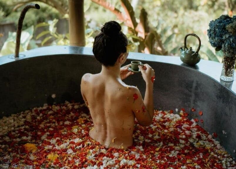 Wanita berendam di bak penuh bunga di Soendaram Spa & Wellness Maha Hills, Sambangan, ID.