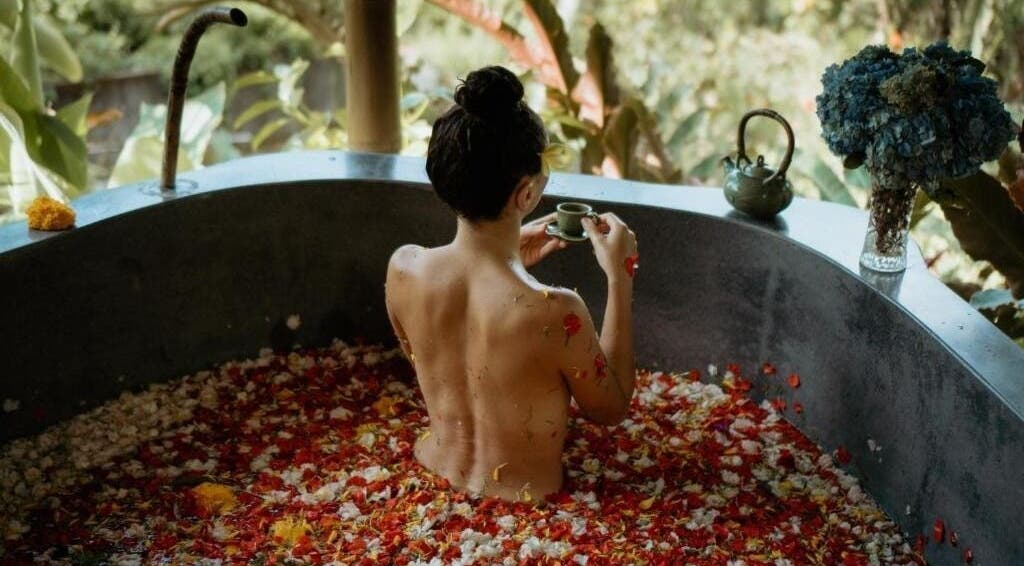 Wanita berendam di bak penuh bunga di Soendaram Spa & Wellness Maha Hills, Sambangan, ID.