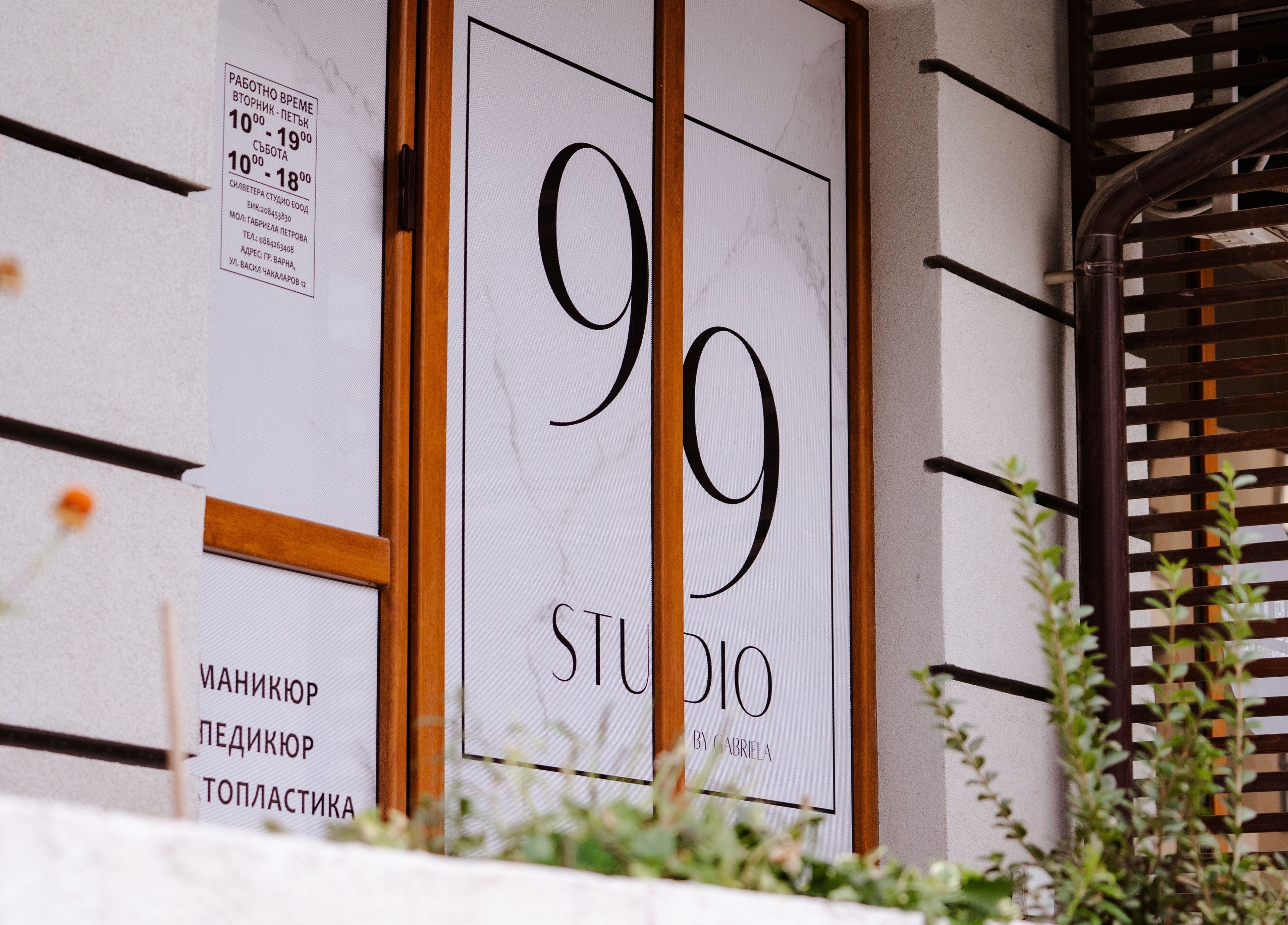 Входът на Studio 99 във Варна, Варна, BG, с модерна дървена рамка и растителност отпред.