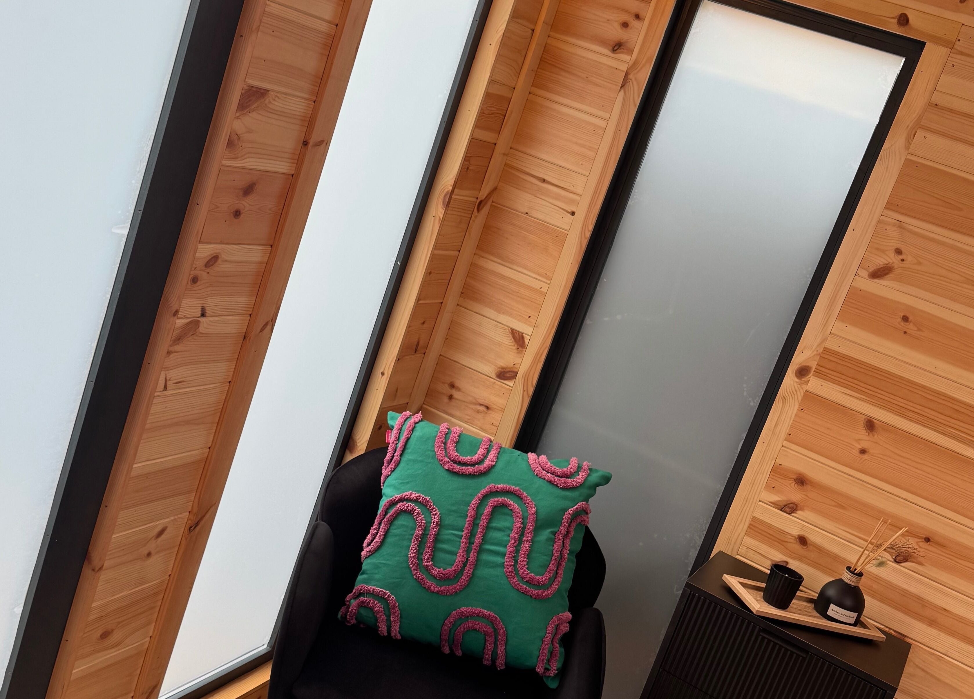 Cozy interior at H L Beauty in Poringland, England, GB featuring wooden walls and a colorful cushion.