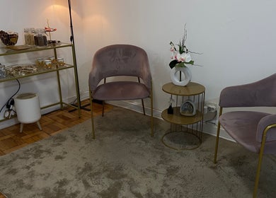 Interior acolhedor do Nallim Nail Studio, Porto, PT, com cadeiras confortáveis e mesa decorativa.