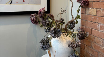 Elegant dried floral arrangement at Lumera Beauty, Droitwich, England, GB, blending with rustic brick wall.