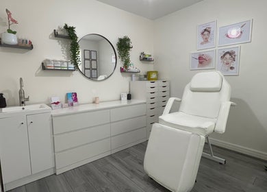 Relaxing treatment room at Lash & Line Studio, Wigan, England, GB with white decor and comfortable chair.