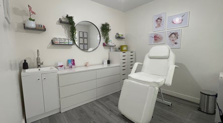 Relaxing treatment room at Lash & Line Studio, Wigan, England, GB with white decor and comfortable chair.
