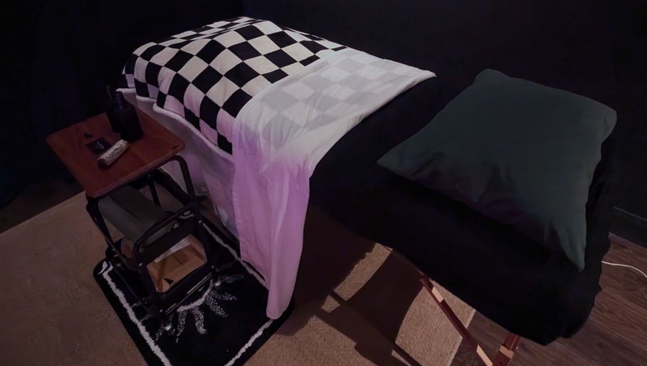 Relaxing massage table at Otta Massage in Glasgow, Scotland, GB with a checkered blanket and dim lighting.