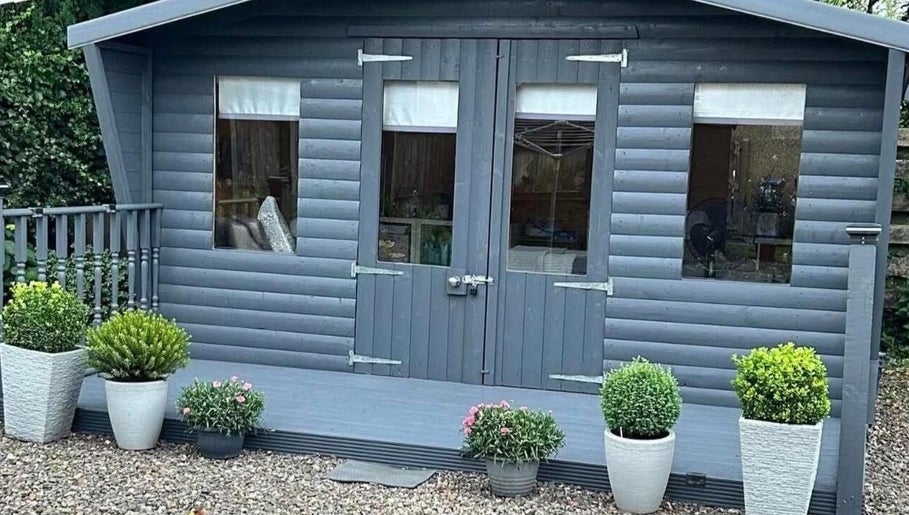 Kirsty’s Beauty Cabin in Cowdenbeath, Scotland. Cozy exterior with potted plants and rustic charm.
