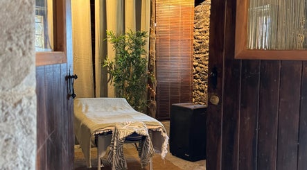 Sala de masaje acogedora en Hub de Bienestar GRS, Graus, Aragón, ES, con mesa y decoración natural.