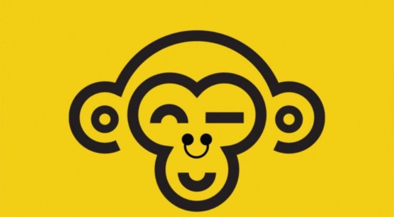 Cheerful monkey logo for Monkey Piercing in Salmiya, Hawalli Governorate, KW, on vibrant yellow background.