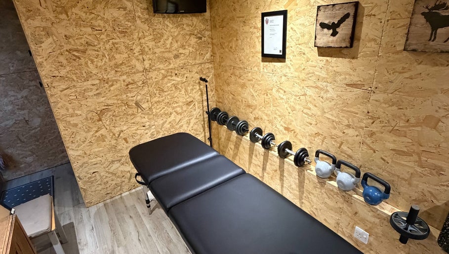 Cozy wellness room at Everything Rehab, Northampton, England, GB, featuring a massage table and weights.