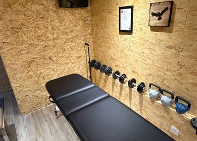 Cozy wellness room at Everything Rehab, Northampton, England, GB, featuring a massage table and weights.