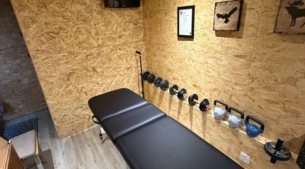 Cozy wellness room at Everything Rehab, Northampton, England, GB, featuring a massage table and weights.