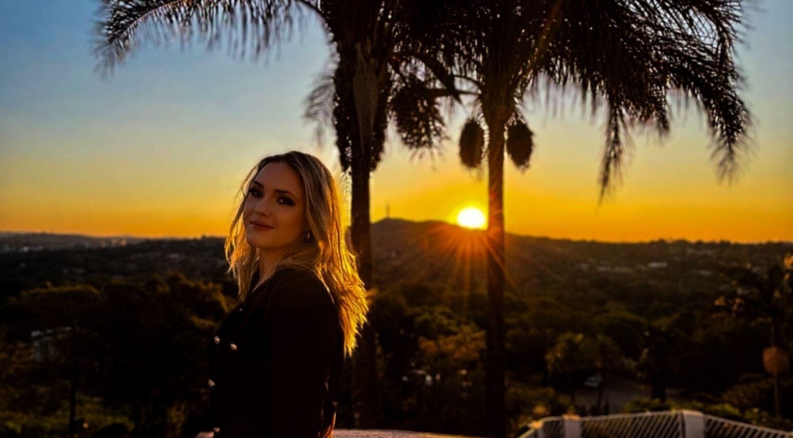 Woman enjoys beautiful sunset view at FVS Photography, Pretoria, Gauteng, ZA with palm trees.