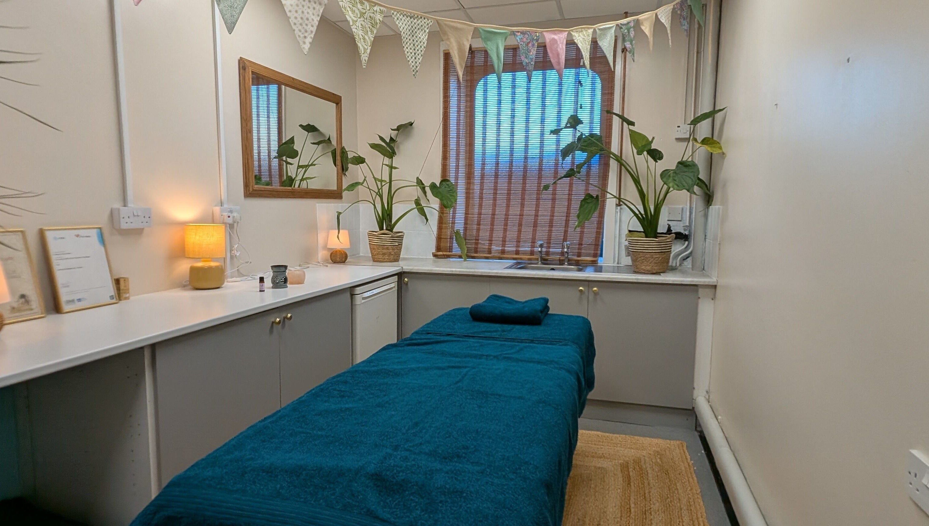 Relaxing treatment room at Wave Massage Studio, Portland, England, GB, with cozy decor and indoor plants.