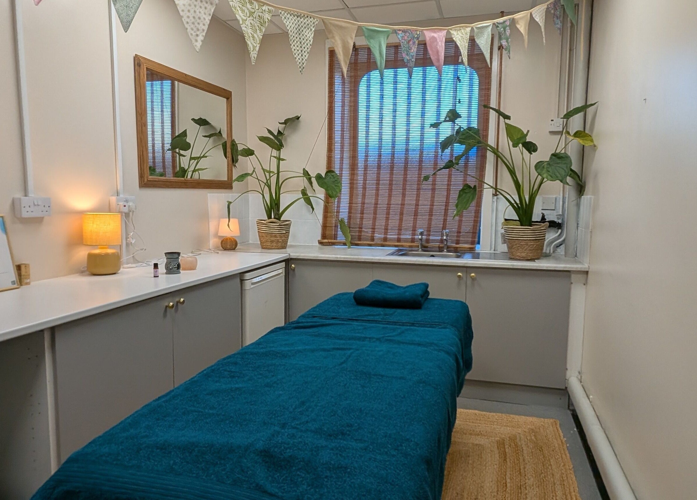 Relaxing treatment room at Wave Massage Studio, Portland, England, GB, with cozy decor and indoor plants.